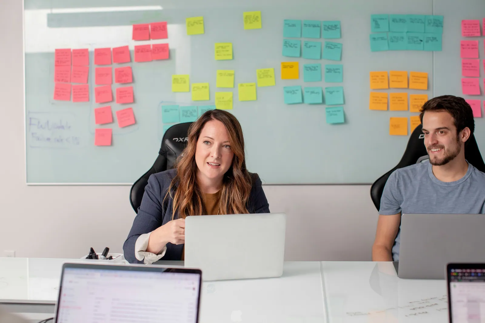 Team members working at laptops in front of a wall of sticky notes